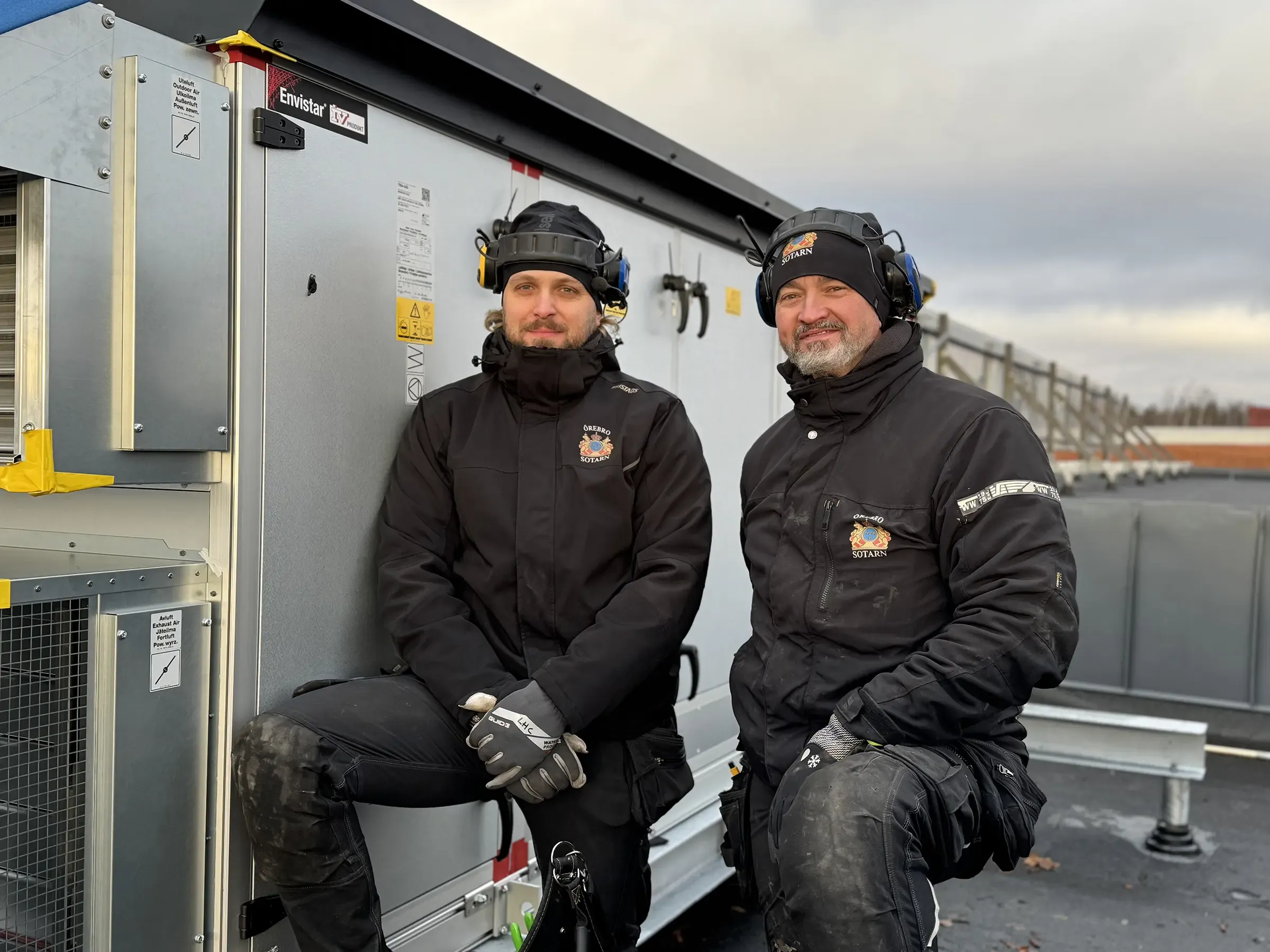 Två personer uppe på ett tak vid ventilation